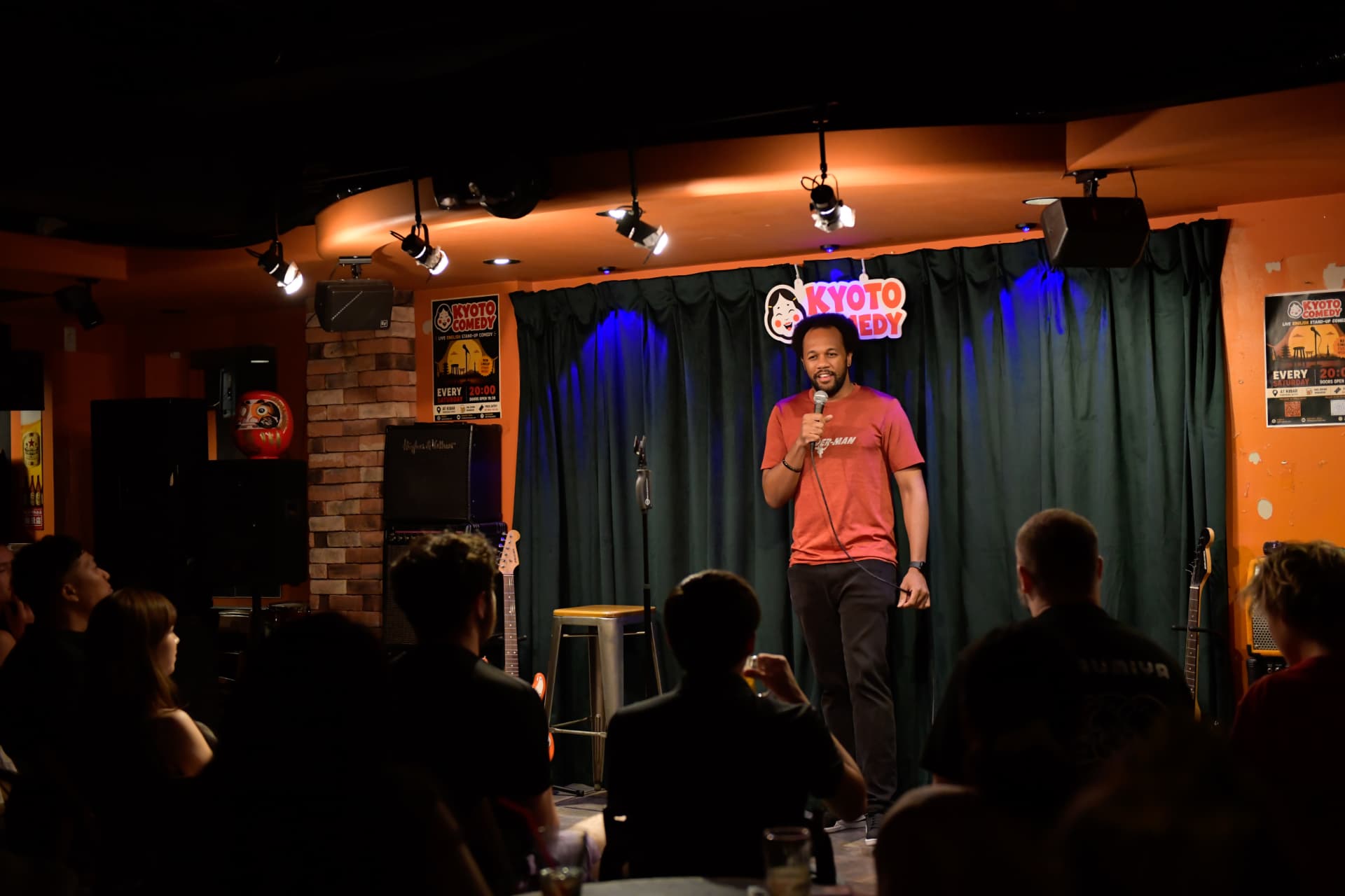 Regular comedian on stage under the Kyoto Comedy sign at Ki Bar in central Kyoto